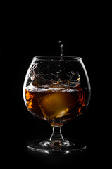 brandy or whiskey pouring into glass on a black background