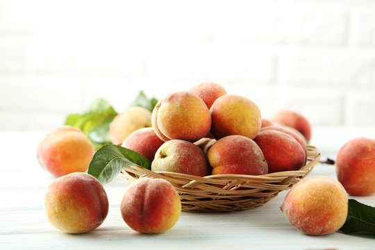 Sweet peach fruit in basket on white wooden table