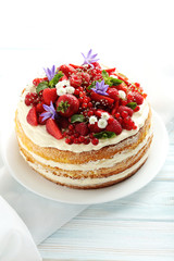 Delicious biscuit cake with berries on blue wooden table