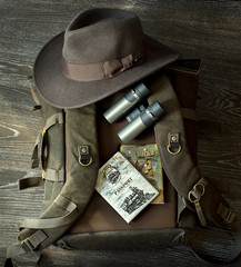Hat, Binoculars, passport, backpack, notepad lie together for travel on wood floor