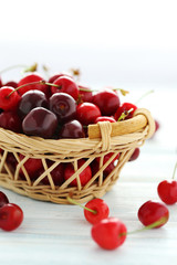 Ripe cherries in basket on a white wooden table
