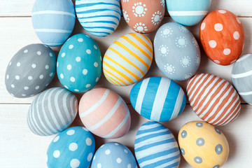 Fototapeta premium Colorful handmade easter eggs lie on white wooden background. Flat lay style