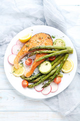 Steak of salmon with asparagus and vegetables on white plate