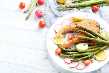 Steak of salmon with asparagus and vegetables on white plate