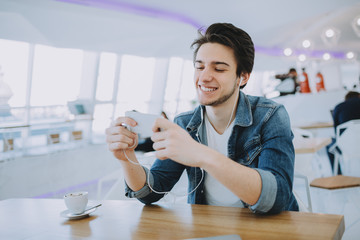Attractive young man or freelance is sitting in cafe and using his mobile