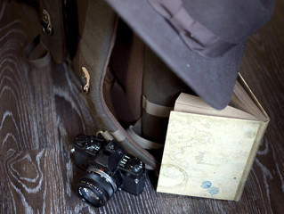 Backpack, camera, hat and notepad on the wood floor