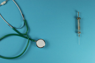 Stethoscope and syringe on blue background. Place for your text.