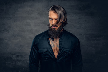 A man with long hair and tattoos on his chest dressed in a black shirt.