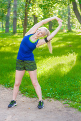 beautiful young woman stretching the muscles of her arms and back before jogging