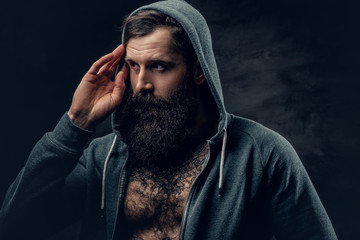 Bearded male with tattoo on a chest, dressed in a grey hoodie.