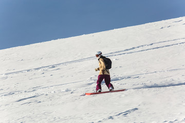 women snowboarder snowboarding on fresh white snow with ski slope on Sunny winter day