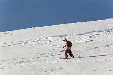 women snowboarder snowboarding on fresh white snow with ski slope on Sunny winter day