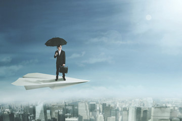 Businessman with umbrella on paper plane