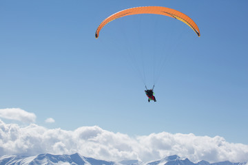 Parachute sky-diver flying in clouds above mountains. Travel adventure concept. space for text