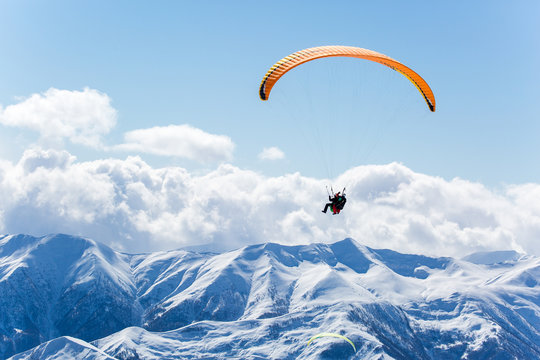 Parachute sky-diver flying in clouds above mountains. Travel adventure concept. space for text