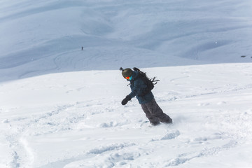  snowboarder snowboarding on fresh white snow with ski slope on Sunny winter day