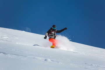  snowboarder snowboarding on fresh white snow with ski slope on Sunny winter day
