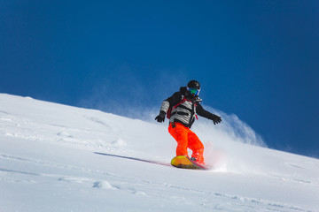  snowboarder snowboarding on fresh white snow with ski slope on Sunny winter day