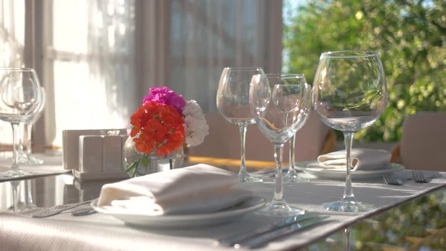 Dinner table, vase with flowers. Empty glasses on white tablecloth.