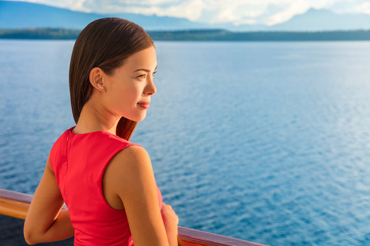 Woman enjoying view of ocean horizon from luxury cruise balcony. Serene ship passenger relaxing outside on suite deck. European travel summer vacation destination.