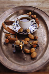 charming vintage still life with Coffee in a porcelain cup, almonds, hazelnuts brown sugar and blueberries  on a bronze dish  