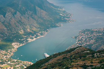 Fototapeta na wymiar Bay of Kotor from the heights. View from Mount Lovcen to the bay. View down from the observation platform on the mountain Lovcen. Mountains and bay in Montenegro. The liner near the old town of Kotor.