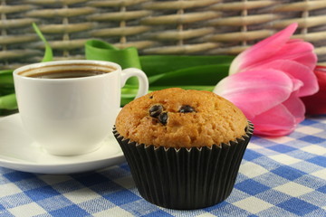 Chocolate muffins with a Cup of coffee and flowers on the table