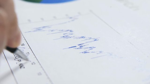 Close up of a man writing math formulas on a blue graph. Concept of exact sciences. Locked down real time close up shot