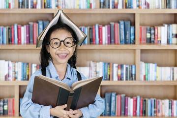 Little girl smiling with book over her head