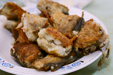 Fried fish and boiled potatoes on a plate.