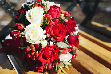 A wedding bouquet of red and white roses on a wooden bench. The bride's bouquet.