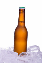 Bottle of beer with drops and ice isolated on white background