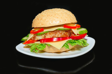 Sandwich with roast pork, cheese and vegetables on the plate and black background
