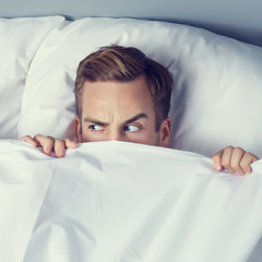 Man peeping from bedsheet