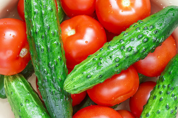 Heap of whole wet tomatoes and cucumbers. Top view point.