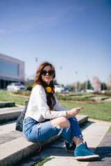 Young woman sitting at the stairs and using mobile pone