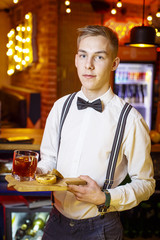 experienced middle age bartender mixologist present mojito style cocktail in old dark modern bar red tie