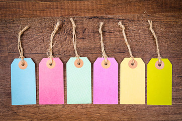 Set of colorful blank hang tag on wooden background.