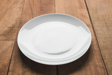Empty white plate on wooden table