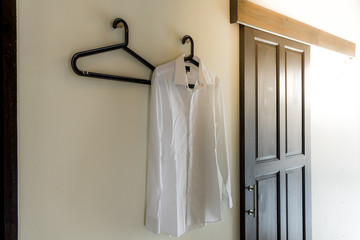 Men's white shirt hanging at the wall with sun flare