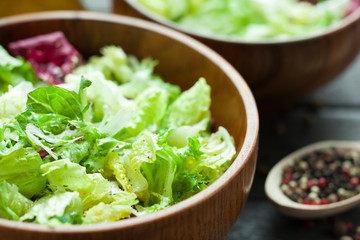 A dish of fresh salad frisse, Romano and radiccio with olive oil, salt and freshly ground percec in a wooden bowl