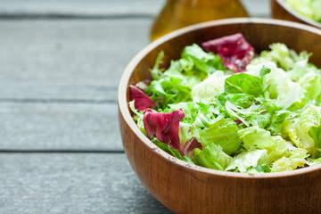 A dish of fresh salad frisse, Romano and radiccio with olive oil, salt and freshly ground percec in a wooden bowl