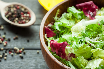 A dish of fresh salad frisse, Romano and radiccio with olive oil, salt and freshly ground percec in a wooden bowl