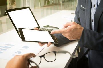 Close-up of male hand, using tablet and computer laptop while sitting at his working place.