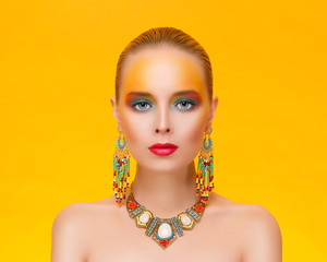 Portrait of a young sexy woman in jewelry on an gold background