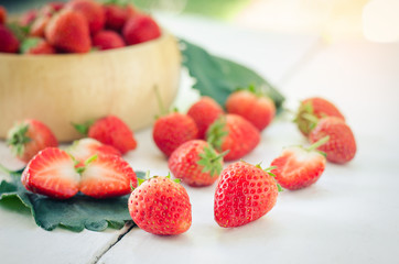 Fresh strawberries in a bowl on wooden background.