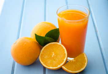 Fresh oranges and juice on the blue wood