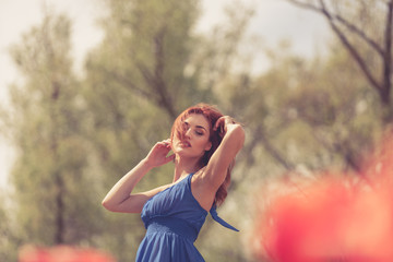 Sensual woman in red flower field in sunny day. Outdoor shooting. Lifestyle and relaxation