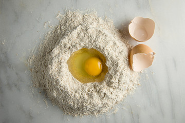 Egg in flour with shells on white marble