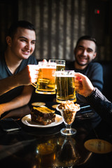 Friends drinking beer and clinking glasses at bar or pub